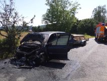 Tři zásahy hasičů v neděli odpoledne: Vzňalo se plně obsazené auto, hořelo v bytě a vůz skončil na boku v porostu