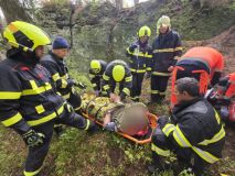 Muž spadl ze skály, měl silné bolesti zad. K sanitce ho nesli hasiči kus nepřístupným terénem