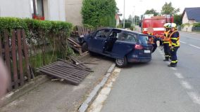Obrazem: Řidička nezvládla své auto a smetla v Bylanech plot, zastavila několik centimetrů od domu