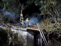 Dům plný nepořádku a obrostlý zelení postihl požár. Hasiči si museli cestu prosekat motorovou pilou
