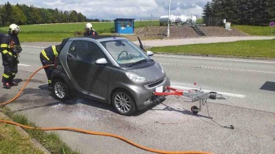 Malý Smart připevněný za obytným autem začal náhle za jízdy hořet