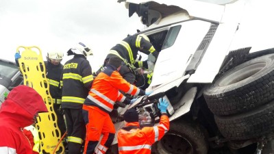 Dvě nákladní auta se střetla v Janově, jedno z nich začalo hořet. Řidiče museli hasiči z kabiny vyprošťovat. Na místě zasahoval i vrtulník